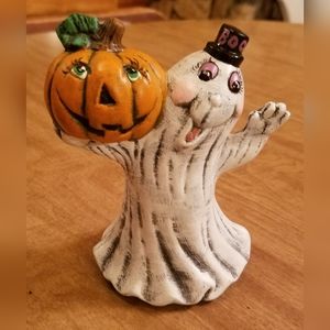 Halloween figurine. Cheerful, friendly ghost carrying a jack o' lantern.